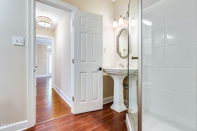 full bath with baseboards, wood finished floors, and a stall shower