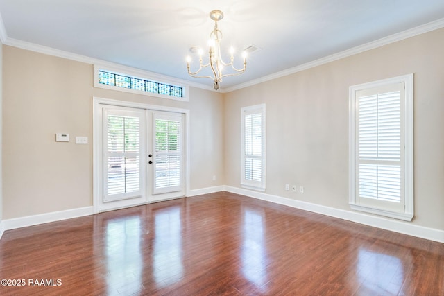empty room with dark wood finished floors, crown molding, french doors, and an inviting chandelier
