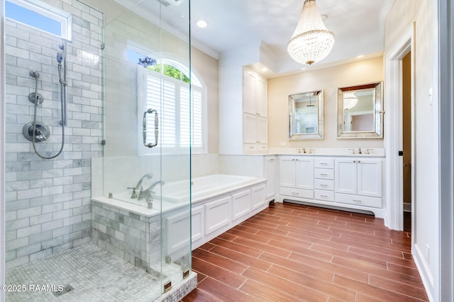 full bathroom with a garden tub, crown molding, wood finished floors, a stall shower, and a chandelier