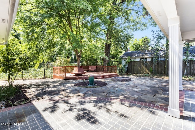 view of patio / terrace featuring a wooden deck, a fenced backyard, and an outdoor fire pit