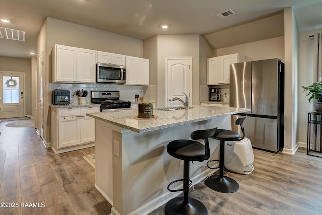 kitchen with visible vents, a sink, light wood-style floors, and appliances with stainless steel finishes