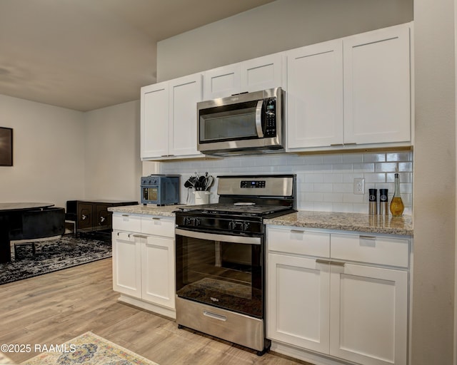 kitchen featuring light wood-style floors, tasteful backsplash, appliances with stainless steel finishes, and white cabinetry