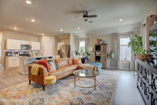 living room featuring ceiling fan, recessed lighting, light wood finished floors, and plenty of natural light