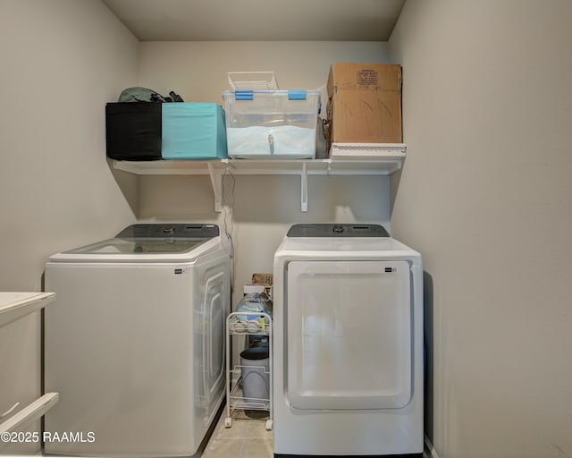 clothes washing area featuring washer and dryer, light tile patterned flooring, and laundry area