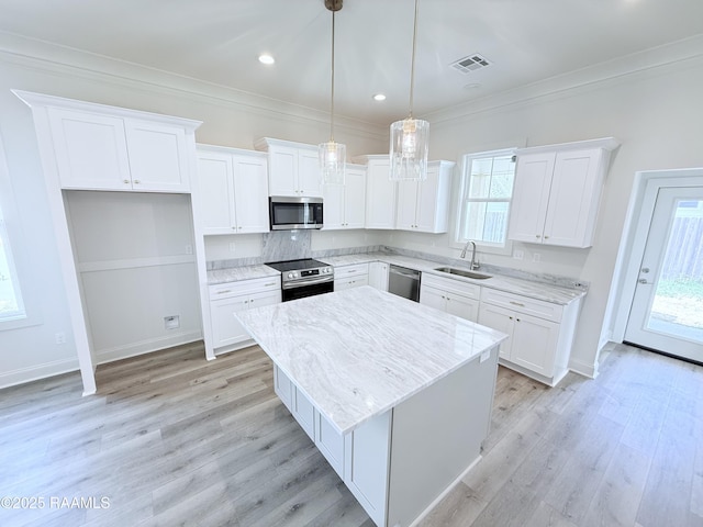 219 Berchman Oaks Dr, Lafayette, LA 70506 - kitchen featuring appliances with stainless steel finishes, a sink, a kitchen island, white cabinets, and ornamental molding