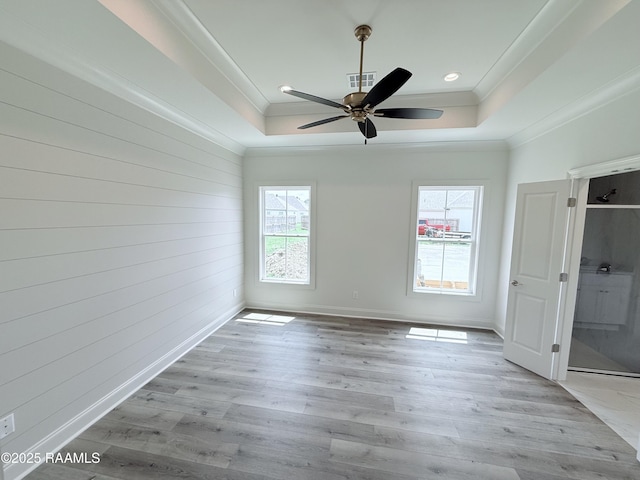 219 Berchman Oaks Dr, Lafayette, LA 70506 - spare room featuring a raised ceiling, ornamental molding, a ceiling fan, wooden walls, and wood finished floors