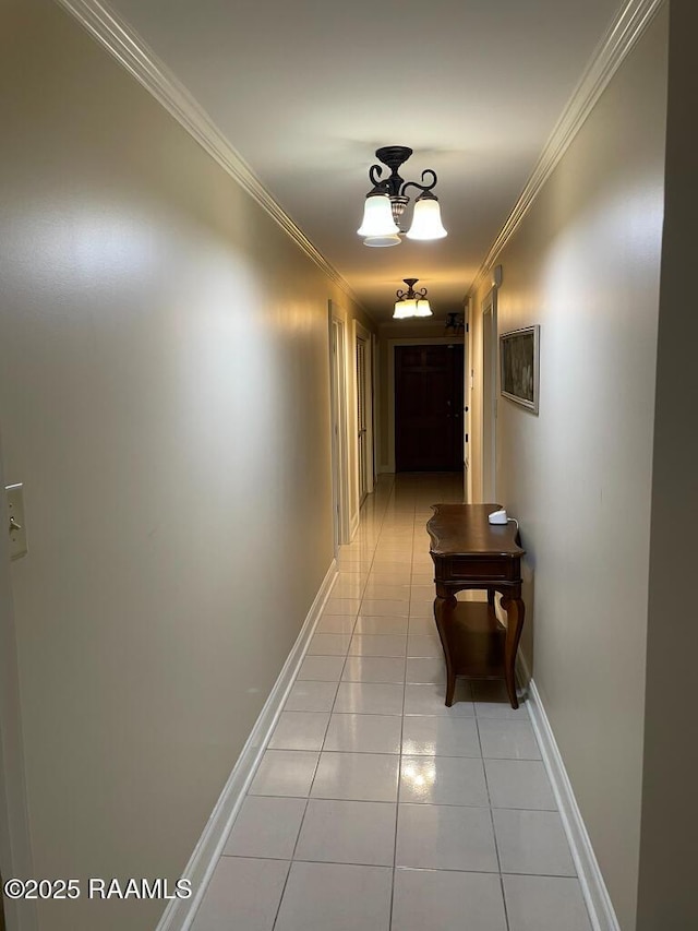 corridor featuring crown molding, baseboards, and light tile patterned floors
