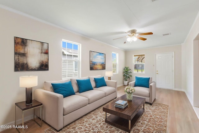 living room with light wood finished floors, crown molding, and baseboards
