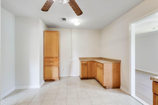 interior space with baseboards, a ceiling fan, and visible vents