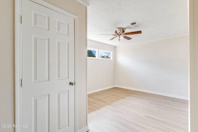 empty room featuring visible vents, ornamental molding, baseboards, light wood-style flooring, and ceiling fan