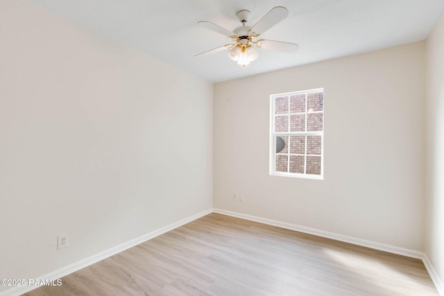spare room with light wood-type flooring, a ceiling fan, and baseboards