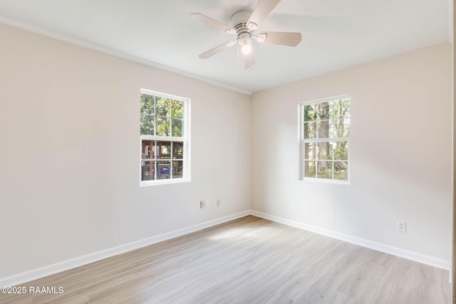 spare room featuring light wood-type flooring, a ceiling fan, and baseboards