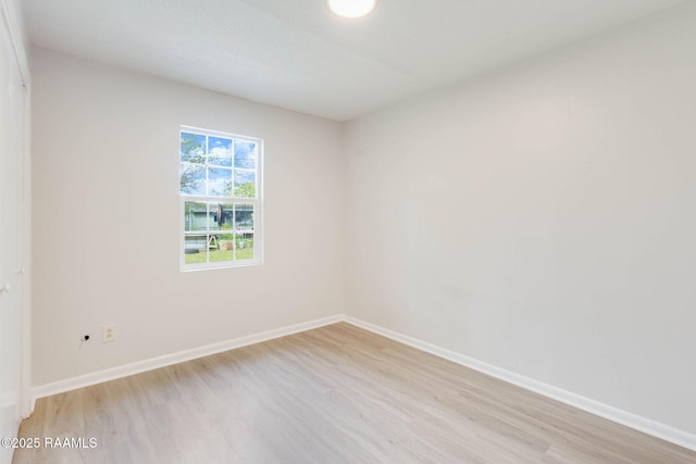 spare room featuring baseboards and light wood-style floors