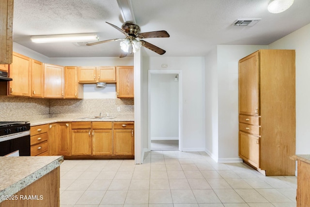 kitchen featuring backsplash, black range with gas stovetop, ceiling fan, and light countertops