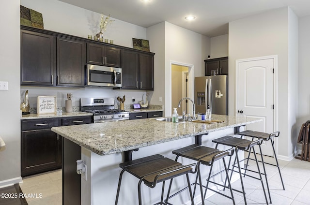 kitchen featuring stainless steel appliances, a breakfast bar, a center island with sink, and light tile patterned flooring