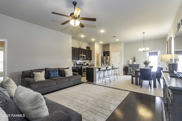 living room with recessed lighting, light wood-style flooring, and ceiling fan with notable chandelier