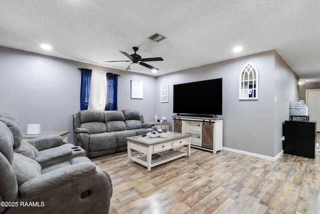 living area featuring light wood-style flooring, a textured ceiling, visible vents, recessed lighting, and a ceiling fan