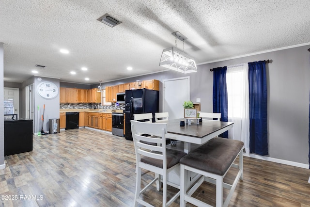 dining room featuring a textured ceiling, light wood-type flooring, visible vents, and baseboards