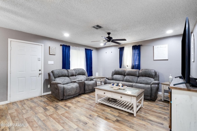 living area with ceiling fan, a healthy amount of sunlight, light wood finished floors, and visible vents