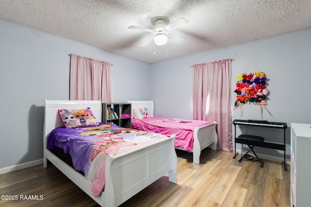 bedroom with baseboards, a ceiling fan, wood finished floors, and a textured ceiling