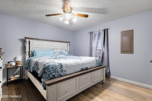 bedroom with wood finished floors, a textured ceiling, electric panel, ceiling fan, and baseboards