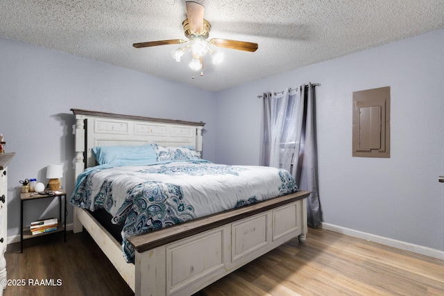 bedroom with wood finished floors, a textured ceiling, electric panel, ceiling fan, and baseboards