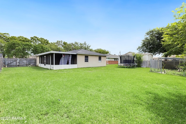 view of yard featuring a fenced backyard, a sunroom, and a trampoline