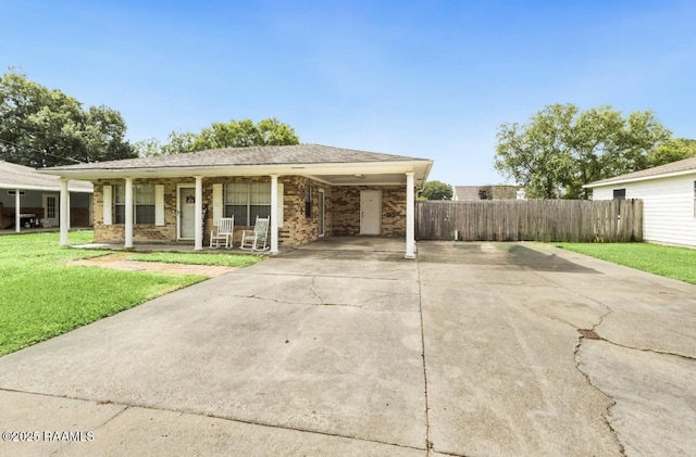 ranch-style house featuring driveway, covered porch, fence, brick siding, and a front yard