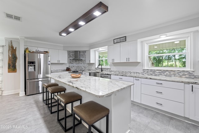 334 Meche Rd, Carencro, LA 70520 - kitchen with appliances with stainless steel finishes, wall chimney range hood, a kitchen island, a kitchen breakfast bar, and backsplash