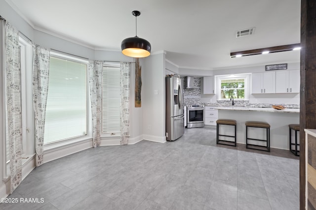 334 Meche Rd, Carencro, LA 70520 - kitchen with appliances with stainless steel finishes, white cabinetry, wall chimney range hood, decorative light fixtures, and a breakfast bar