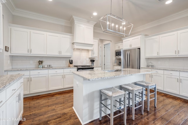 kitchen featuring a sink, a breakfast bar, white cabinets, appliances with stainless steel finishes, and recessed lighting