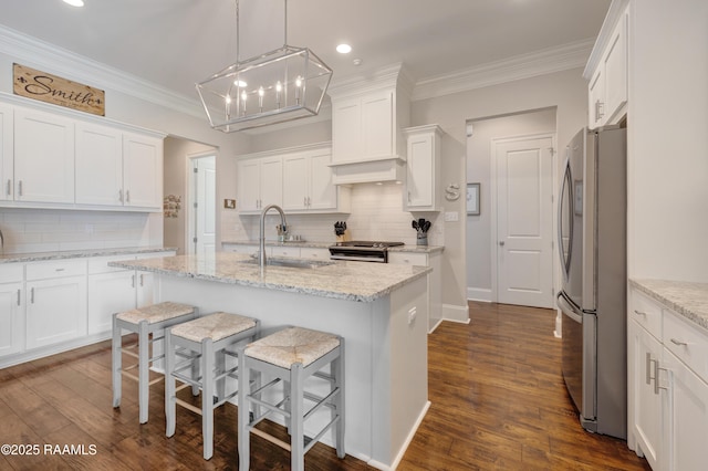 kitchen with white cabinets, appliances with stainless steel finishes, an island with sink, and a sink