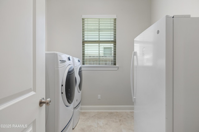 laundry room with baseboards, washing machine and clothes dryer, laundry area, and light tile patterned floors