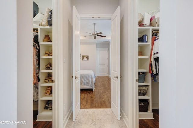 spacious closet with a ceiling fan and light wood-style flooring
