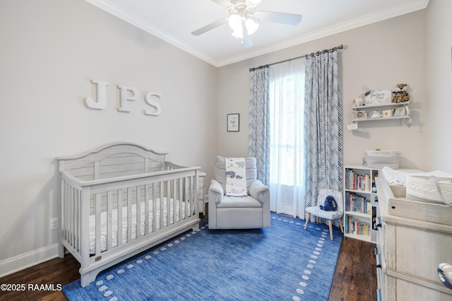 bedroom with a crib, wood finished floors, a ceiling fan, ornamental molding, and baseboards