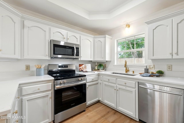 kitchen featuring ornamental molding, light countertops, white cabinets, a sink, and stainless steel appliances