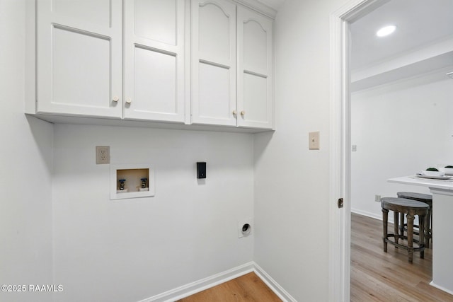 clothes washing area with electric dryer hookup, cabinet space, baseboards, hookup for a washing machine, and light wood-style floors