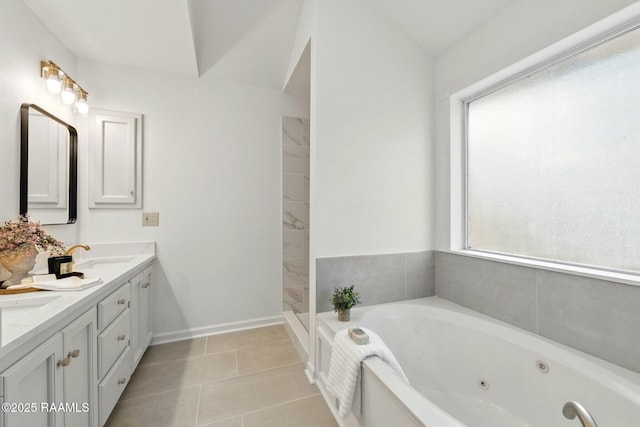full bath with a tub with jets, double vanity, a sink, and tile patterned floors
