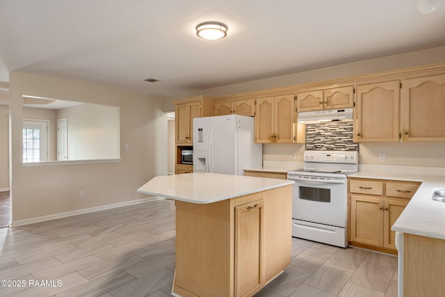kitchen featuring light countertops, a center island, light brown cabinetry, under cabinet range hood, and white appliances