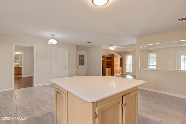 kitchen featuring light brown cabinets, a center island, visible vents, baseboards, and light countertops