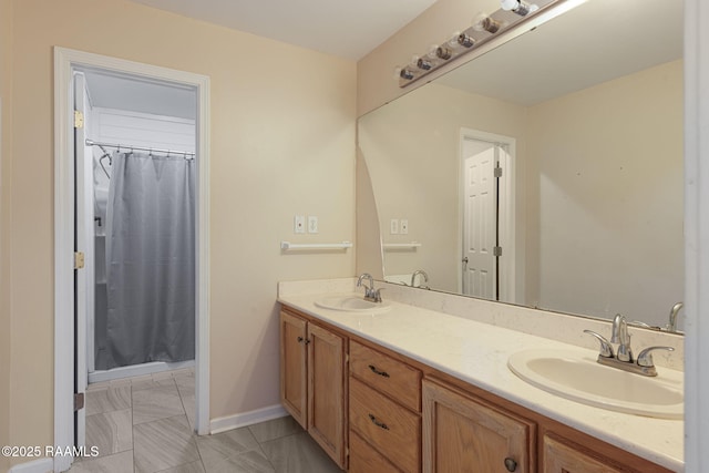 bathroom featuring a shower with curtain, double vanity, a sink, and baseboards