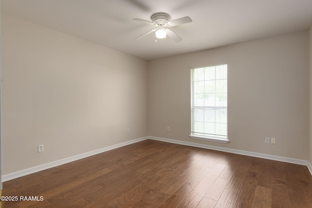 unfurnished room featuring dark wood-type flooring, a ceiling fan, and baseboards