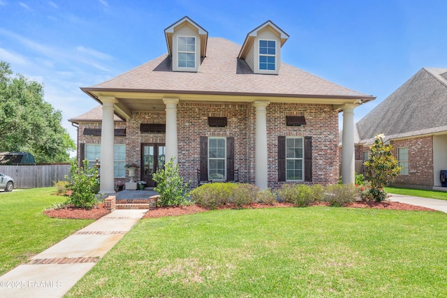 view of front of property featuring fence, a shingled roof, brick siding, a front yard, and covered porch
