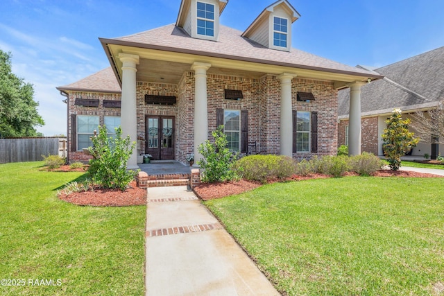 view of front facade with french doors, a front yard, roof with shingles, brick siding, and fence