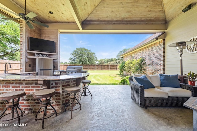 view of patio / terrace with grilling area, a sink, a fenced backyard, an outdoor kitchen, and outdoor wet bar