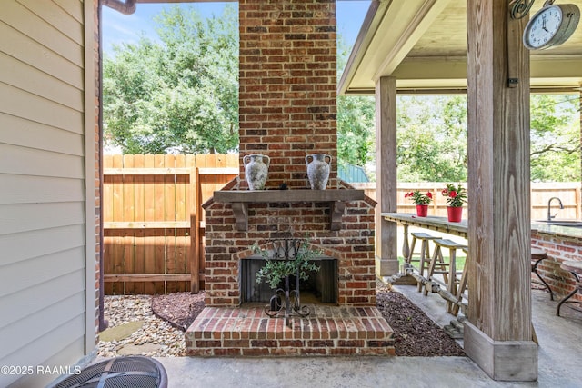 view of patio / terrace with fence, an outdoor brick fireplace, and central AC