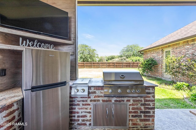 view of patio with an outdoor kitchen, fence, and a grill