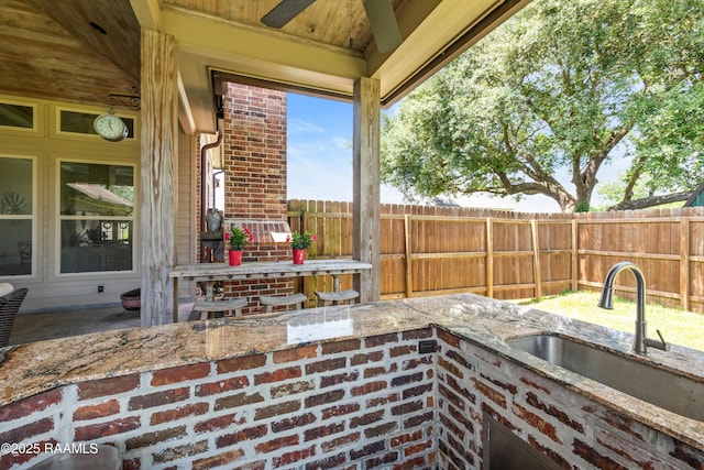 view of patio featuring a sink, fence, and a ceiling fan