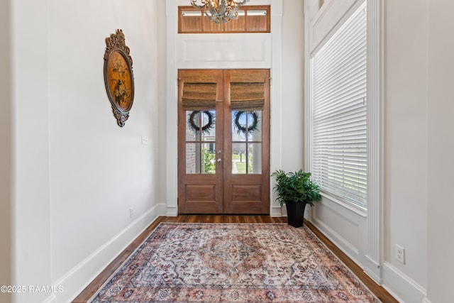 entrance foyer with an inviting chandelier, plenty of natural light, wood finished floors, and french doors