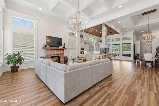 living area with a brick fireplace, a chandelier, a healthy amount of sunlight, and a towering ceiling